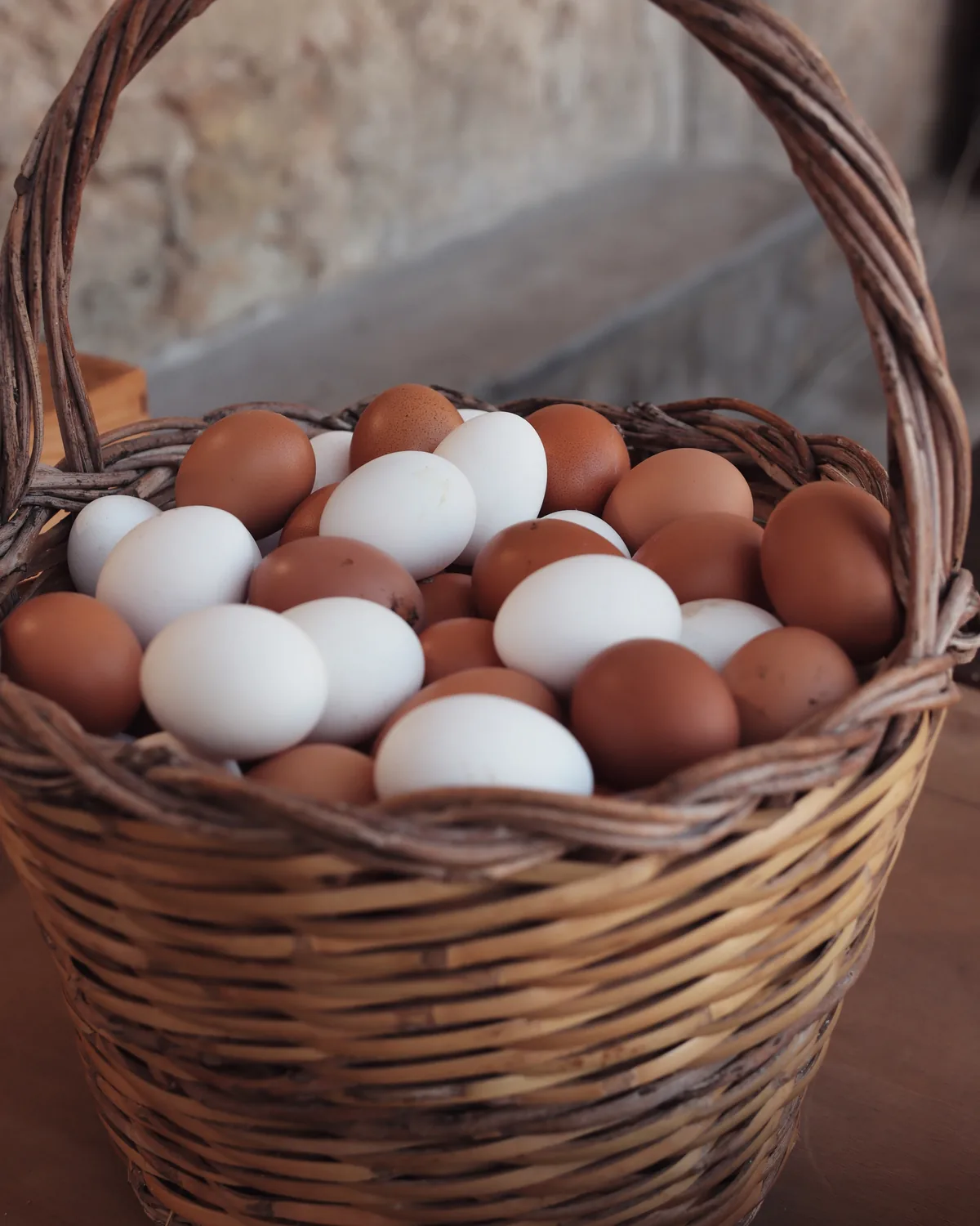 Cesto di vimini colmo di uova fresche bianche e marroni di Castelbio